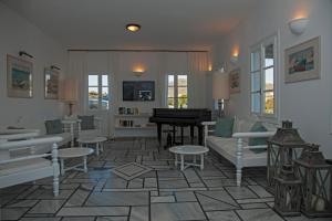 een woonkamer met witte meubels en een piano bij Parian Village Beach Hotel - Adults Only in Parikia