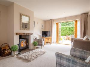 a living room with a fireplace and a tv at Teagles Cottage in Stow on the Wold