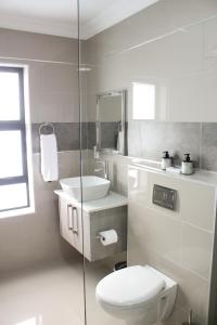 a white bathroom with a toilet and a sink at Elizabeth House in Hermanus