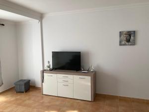 un soggiorno con TV a schermo piatto su una parete bianca di MARTSARAs PLAYA SARDINA a Sardina