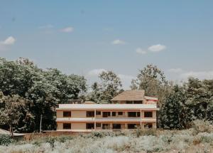 a building in a field with trees in the background at Villa Viva Tanzania in Arusha