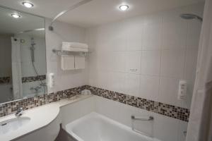 a bathroom with a tub and a sink and a mirror at Holiday Inn London Brentford Lock, an IHG Hotel in Brentford