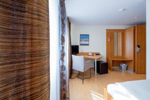 Zimmer mit einem Bett und einem Zimmer mit einem Schreibtisch in der Unterkunft Hotel Am Froschbächel in Bühl