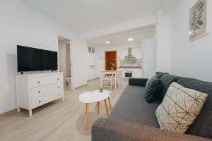 ein Wohnzimmer mit einem Sofa, einem TV und einem Tisch in der Unterkunft Top2Stay Alhóndiga in Málaga