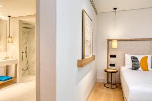 a bedroom with a bed and a bathroom with a shower at Vathi Cove Luxury Resort & Spa in Chrysi Ammoudia