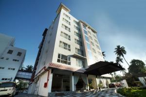 a tall white building with a palm tree in front of it at Vivin Luxury Suites in Trivandrum