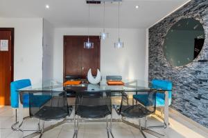 a dining room with a glass table and blue chairs at Elan Rimal 5 Suites in Dubai