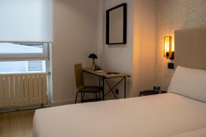 Habitación de hotel con cama y escritorio en Hotel Alda Orzán en A Coruña