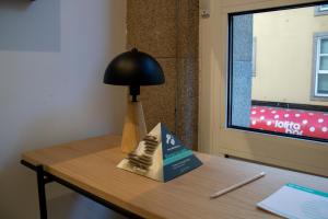 une lampe assise sur une table à côté d'un bureau avec une lampe dans l'établissement Hotel Alda Orzán, à La Corogne