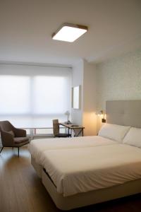 a bedroom with a large bed and a chair at Hotel Alda Orzán in A Coruña