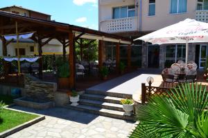 eine Terrasse mit einem Sonnenschirm, Tischen und Stühlen in der Unterkunft Saint George Family Hotel in Lozenets