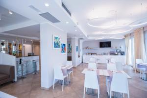 a dining room with white tables and white chairs at Hotel Baby in Rimini