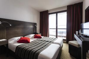 um quarto de hotel com uma cama grande com almofadas vermelhas em Hôtel Tignes Le Diva em Tignes