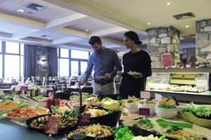 dos personas parados frente a un buffet de comida en Hôtel Tignes Le Diva en Tignes