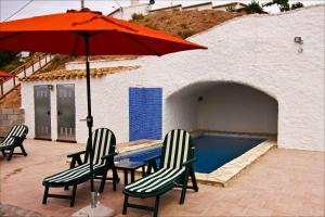 een tafel en stoelen met een parasol naast een zwembad bij Cueva Pura Vida in Pulpite