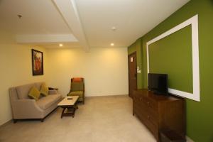 a living room with a couch and a tv at Vivin Luxury Suites in Trivandrum