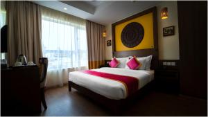 a hotel room with a large bed with pink pillows at Vivin Luxury Suites in Trivandrum