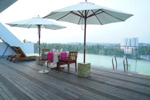 a table and chairs with umbrellas on a deck at Vivin Luxury Suites in Trivandrum