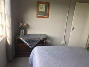 Un dormitorio con una cama y una mesa con flores. en Meshlynn farm cottage, en Thendele