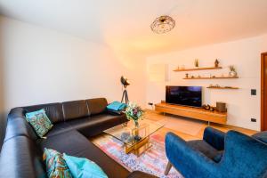 a living room with a black leather couch and two blue chairs at Loft 1453 in Ludwigshafen am Rhein