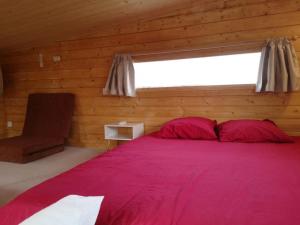 Le Petit Chalet de Nîmes Shantay Youstay في نيم: غرفة نوم بسرير احمر كبير ونافذة