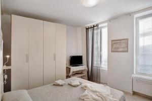 a white bedroom with a bed and a television at Casa via Montà in centro in Sanremo