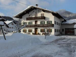 Una gran casa blanca con nieve en el suelo en Schwaigerhof, en Marquartstein
