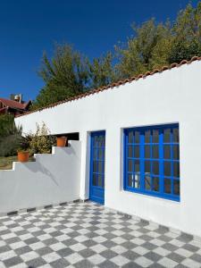 a white house with blue doors and a checkered floor at Clara en el Cerro in Tandil