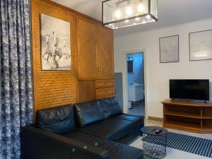 salon z czarną kanapą i telewizorem w obiekcie Viki Apartmanház w mieście Dorog