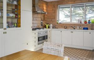 a kitchen with white cabinets and a wooden wall at Finnhouse in Bergen aan Zee