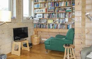 a living room with a green chair and a book shelf with books at Finnhouse in Bergen aan Zee