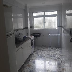 a white kitchen with a sink and a window at cantinho do Xavier in São Vicente