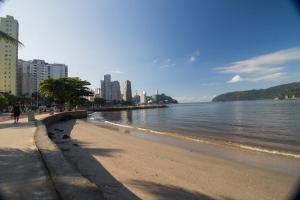 a beach with people walking on it next to the water at cantinho do Xavier in São Vicente