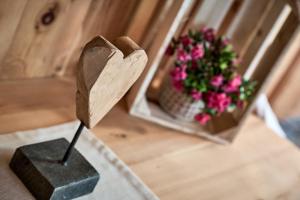 un corazón de madera en un puesto junto a un jarrón de flores en Blasigsuite Blasighof, en Racines