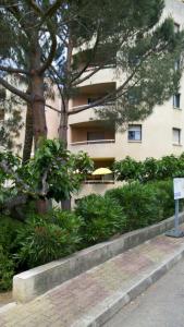 a building with trees and bushes in front of a building at Chambre d'hôte Les Jardins Du Forcone in Ajaccio