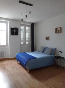 una camera da letto con un letto con lenzuola blu e una finestra di Appartement cosy au coeur de la ville d'Auch ad Auch