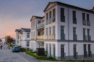 ein weißes Gebäude mit einem davor geparkt in der Unterkunft Westendpalais 04 Strandburg in Ahlbeck