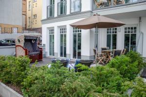 eine Terrasse mit einem Tisch, einem Sonnenschirm und Stühlen in der Unterkunft Westendpalais 04 Strandburg in Ahlbeck