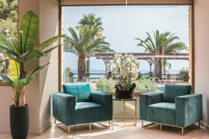 a lobby with two blue chairs and palm trees at Makis Hotel in Skala Kefalonias