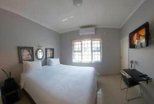 a bedroom with a large white bed and a window at Twenty4ten Guesthouse in Gaborone