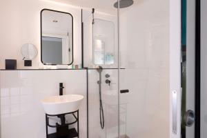 a white bathroom with a sink and a mirror at Le 12 Hôtel in Paris
