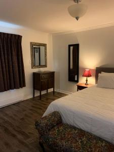 ein Schlafzimmer mit einem Bett, einem Stuhl und einem Spiegel in der Unterkunft Lakelawn B&B and Motel in Yarmouth
