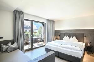 a bedroom with a large bed and a balcony at Alpinhotel Keil in Valdaora