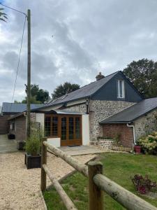 a brick house with a fence in front of it at Les 4 seasons, agréable gîte avec terrasse et jardin in Croix Bigot