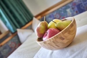 a wooden bowl of apples and pears on a bed at Ratschingser Kreuz Blasighof in Racines