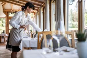 a woman standing at a table in a restaurant at Hotel Steger-Dellai in Alpe di Siusi