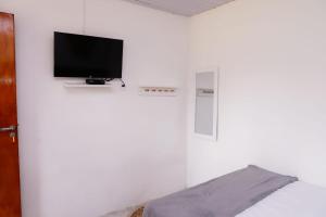 a bedroom with a bed with a tv on a wall at CASA PITANGA in Fernando de Noronha