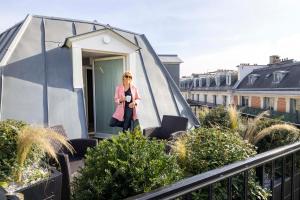 a woman standing on the balcony of a house at Le 12 Hôtel in Paris