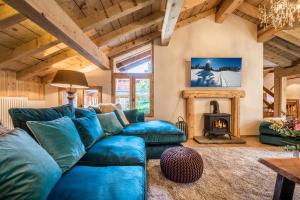 a living room with a blue couch and a fireplace at Chalet Chu Lo Dou Le Praz Courchevel - by EMERALD STAY in Courchevel