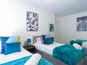 two beds in a room with blue and white at Tudors eSuites 4 Bedroom House with Garden & 9 Beds in Coventry